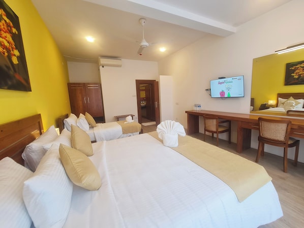 A hotel room with two beds, a desk, a television, and a bathroom visible through an open door. - The Dorwin Heights (Kandy)