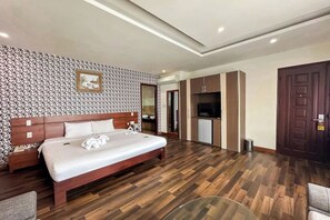 Habitació d'hotel amb un llit de fusta, una televisió, armaris i un armari.