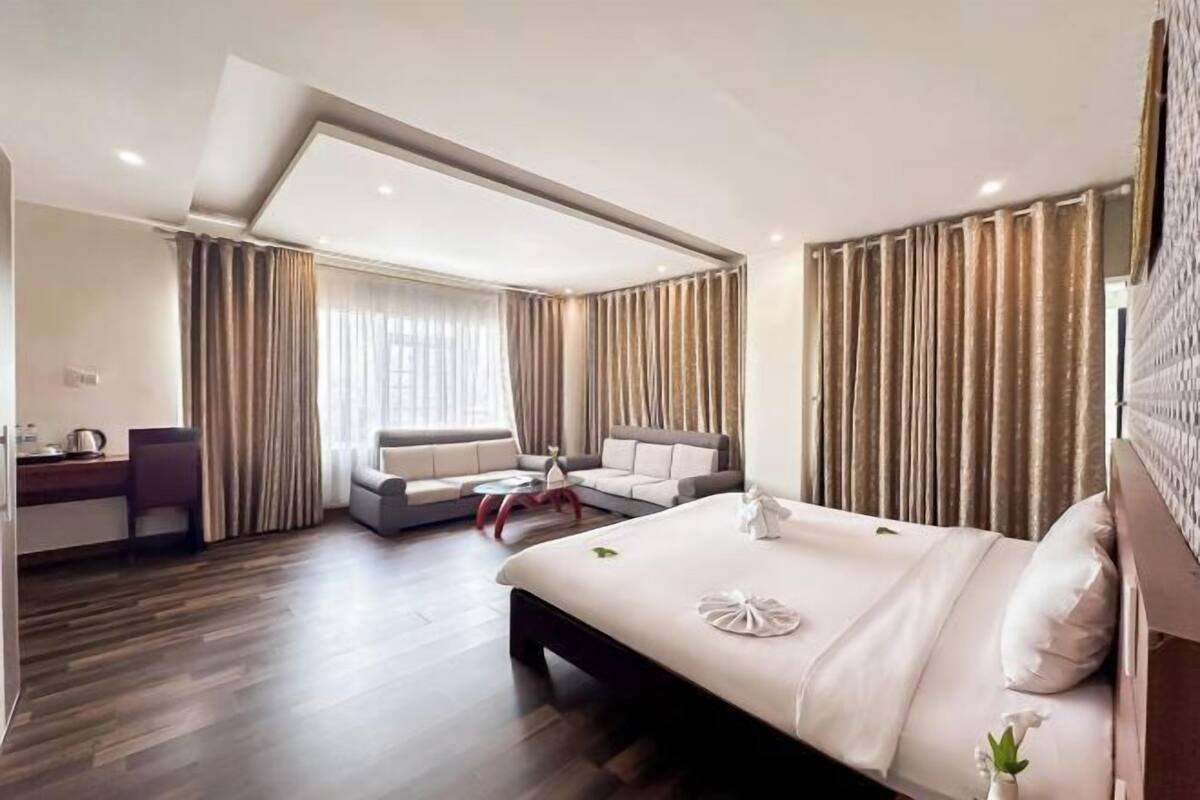 Una habitación de hotel moderna con cama, sofá, una mesita y un escritorio.