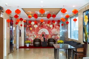 Vestíbulo de hotel con mostrador de recepción, zona de estar y elementos decorativos como faroles colgantes.