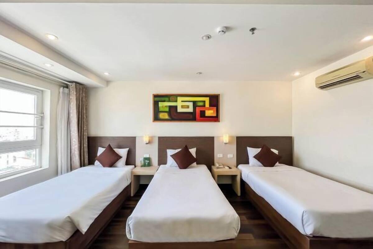 Habitación de hotel con dos camas individuales, un ventanal grande y un cuadro abstracto moderno en la pared.