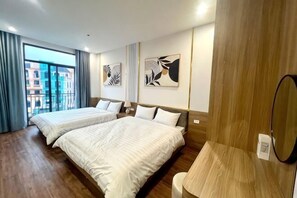 A hotel room with two beds, a wooden floor, a large window, and artwork on the walls. - Homestay SWAN BY KAT (Nghia Tru)