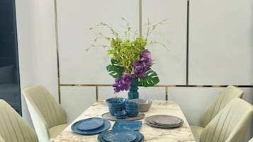 A dining table set with blue plates and a vase with purple flowers.