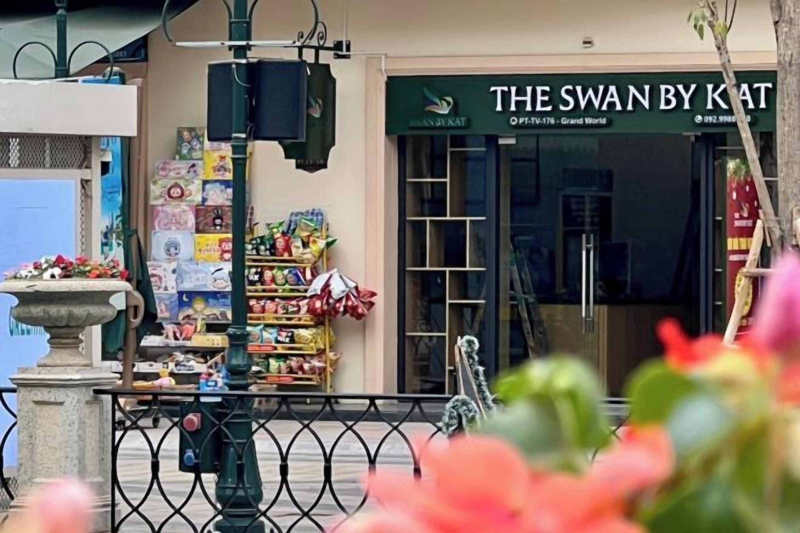 A storefront with a sign reading 'THE SWAN BY KAT' and a variety of items displayed outside.