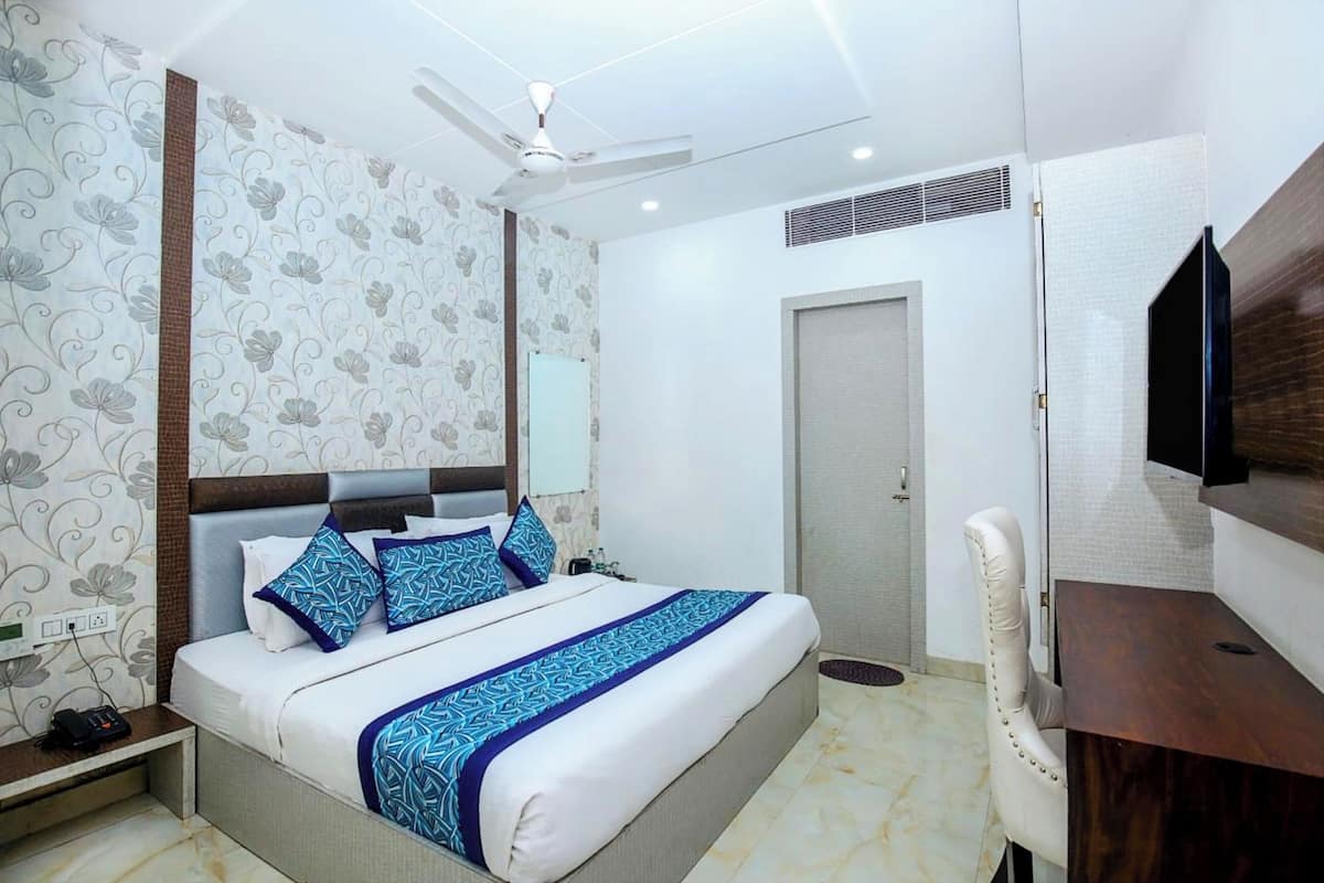 Une chambre d’hôtel équipée d’un lit, d’un bureau, d’une chaise, d’une télévision, d’un ventilateur de plafond et d’une porte.