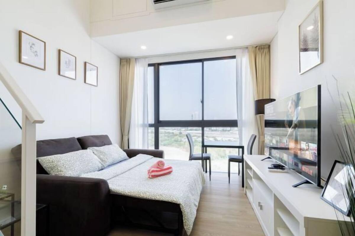 Ein modernes Hotelzimmer mit Bett, Fernseher, Schreibtisch und großem Fenster.