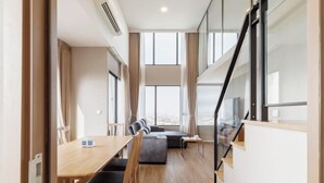 A modern hotel room with a dining area, a sofa, and a staircase. - Loft Apartments in Bangkok near Jodd Night Market [Nearly 711+ Central Pharam 9 Shopping Center] (Bangkok)