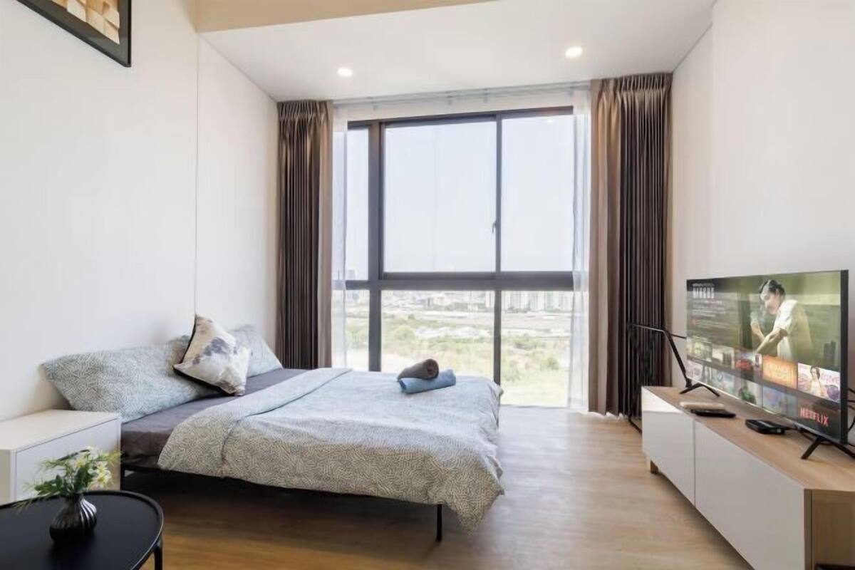 Ein modernes Hotelzimmer mit einem großen Bett, einem Fernseher und Blick auf die Stadt.