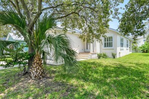 A single-story house with a front porch, a palm tree, and a well-maintained lawn.
