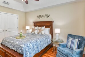 A bedroom with a bed, a chair, a nightstand, and a wall decoration.