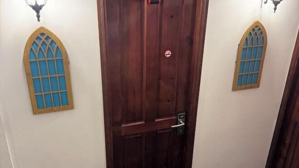 Een houten deur met een raam en een deurbel.