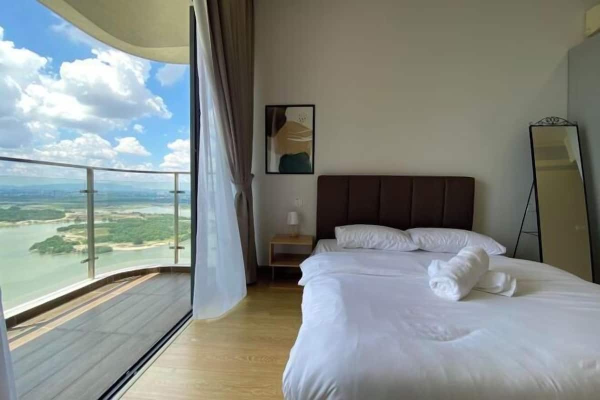 A hotel room with a bed, a nightstand, a mirror, a painting, and a balcony with a view of the landscape.
