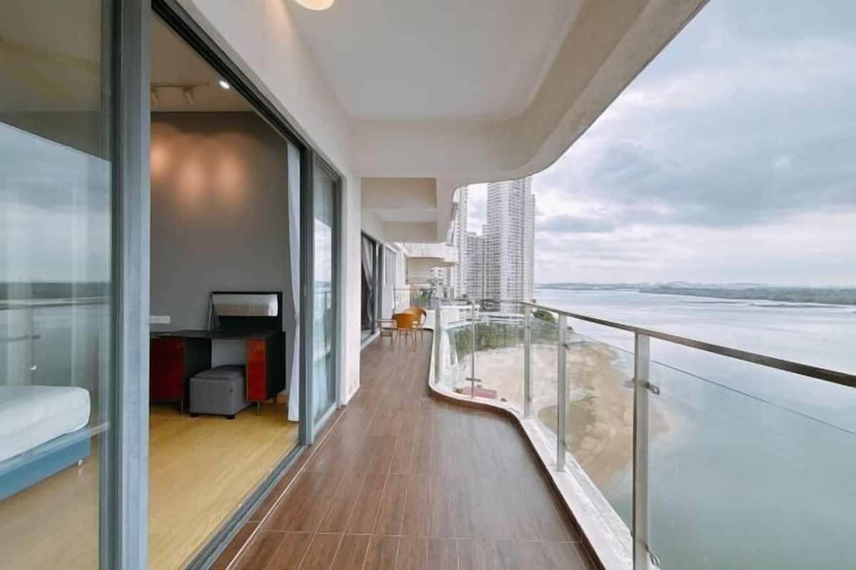 A modern balcony with a view of the sea, a seating area, and a small kitchenette.