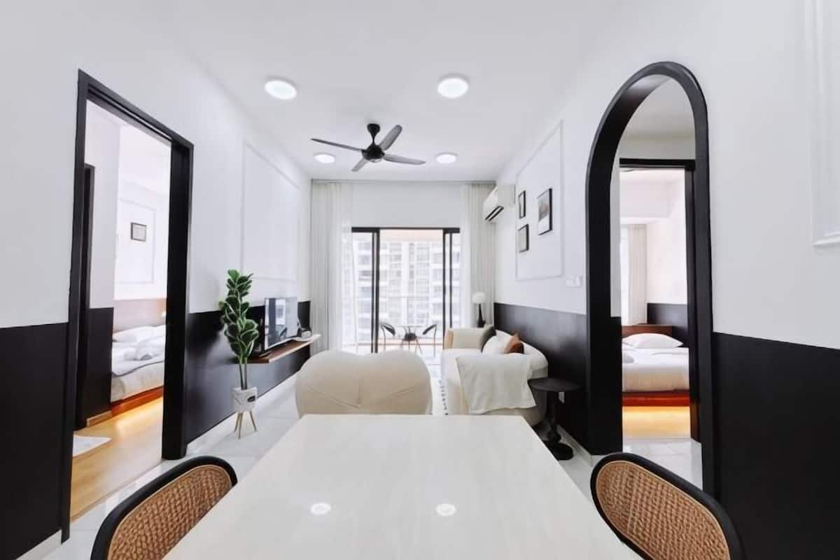 A hotel room with a large bed, a desk with a chair, a TV, and a ceiling fan.