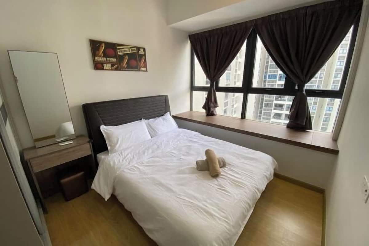 A hotel room with a bed, a nightstand, a window with curtains, and a wall-mounted picture.