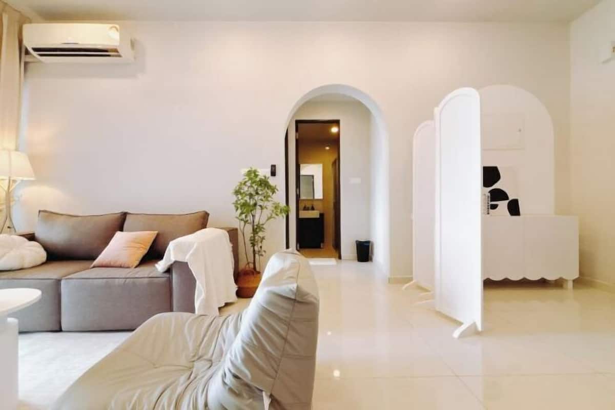 A modern living room with a sofa, a potted plant, and a white cabinet.