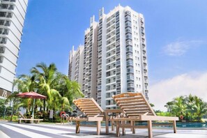 A high-rise building with a pool area featuring lounge chairs and umbrellas. - Scenic Country Garden Danga Bay by Lions Bay (Johor Bahru)