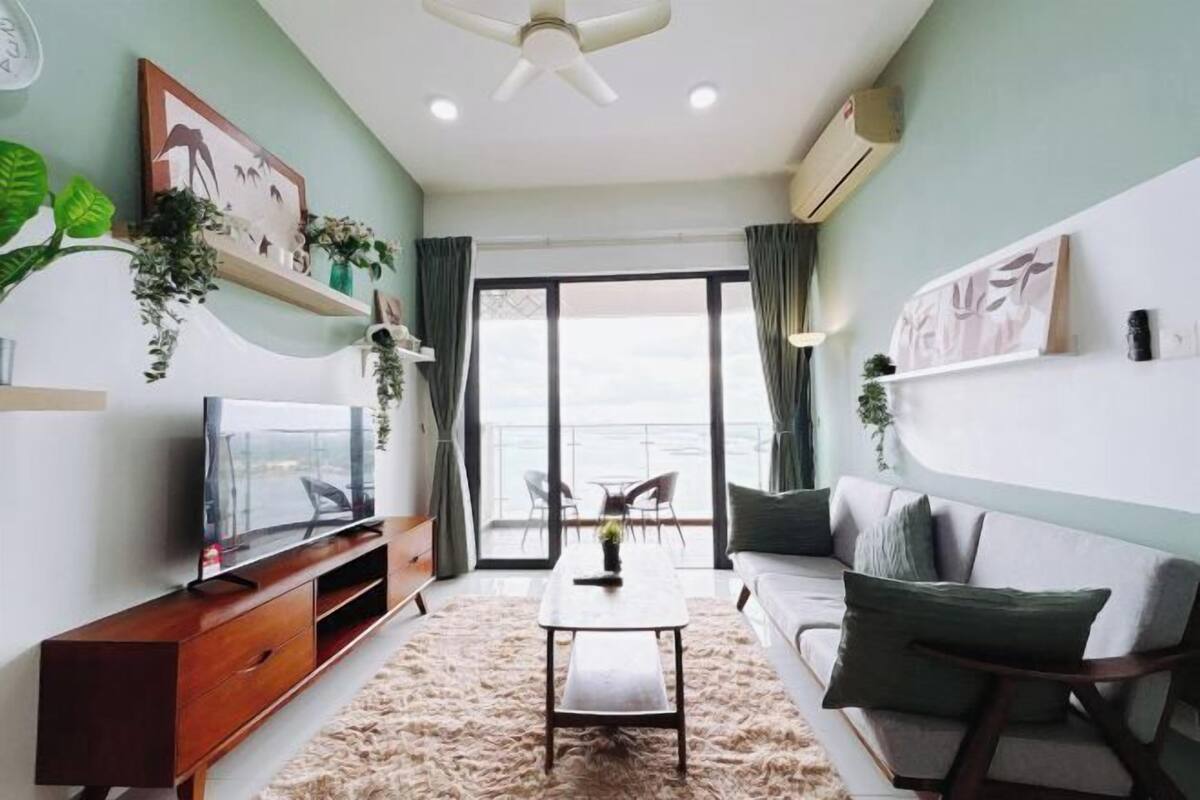 A modern living room with a flat-screen TV, a coffee table, a sofa, and a large window with curtains.