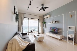 En moderne stue med sofa, sofabord, fjernsyn og en balkon med udsigt.