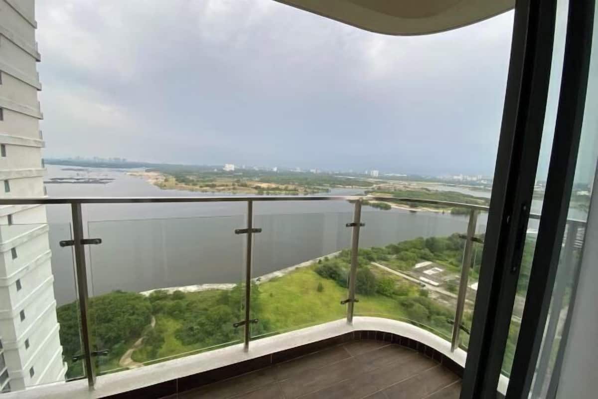 A balcony with a view of a river and greenery.