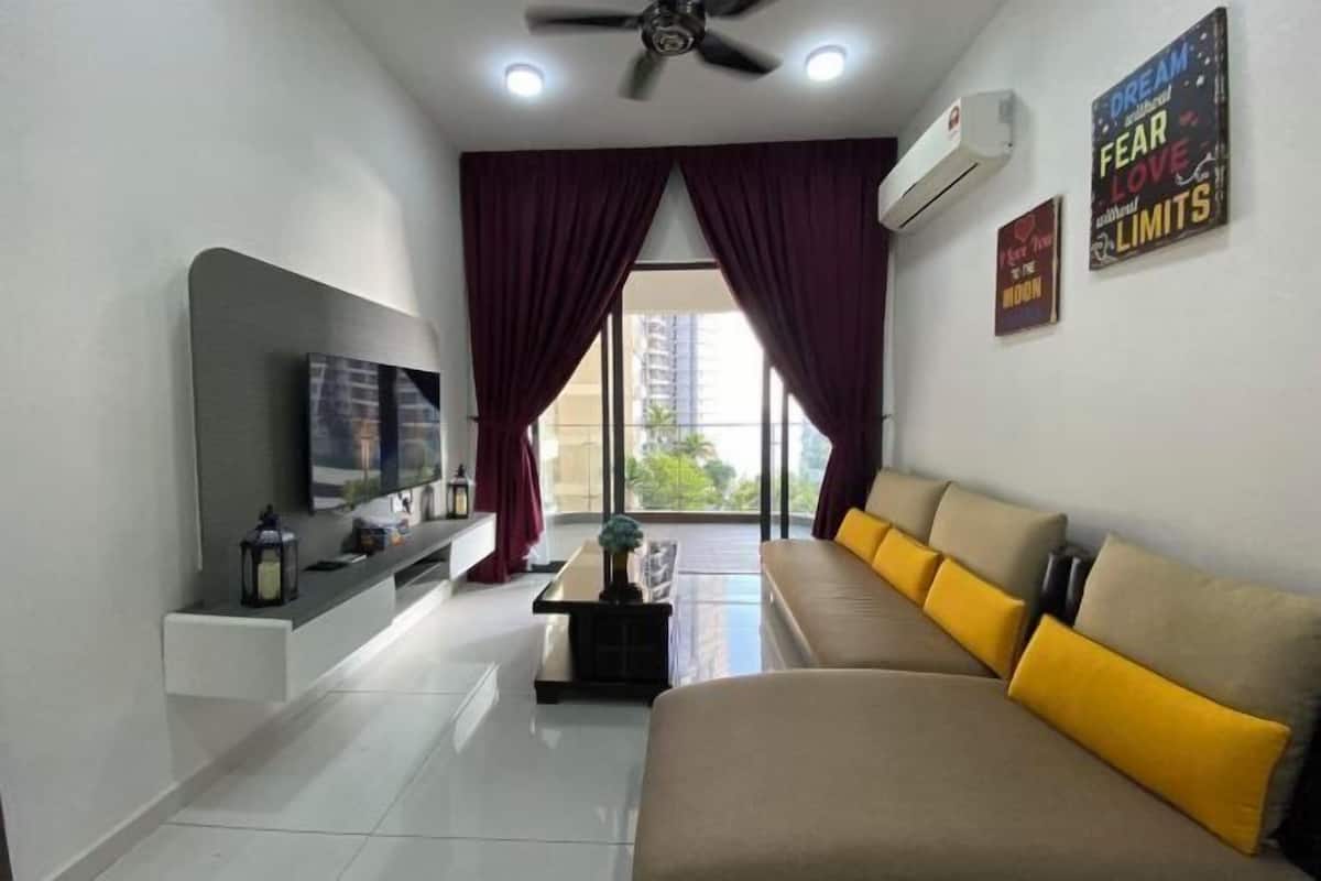 A living room with a sofa, a TV, a ceiling fan, and a window with curtains.