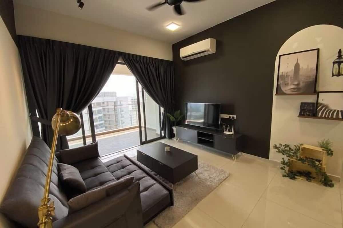 A modern living room with a sofa, coffee table, TV, and large windows with curtains.