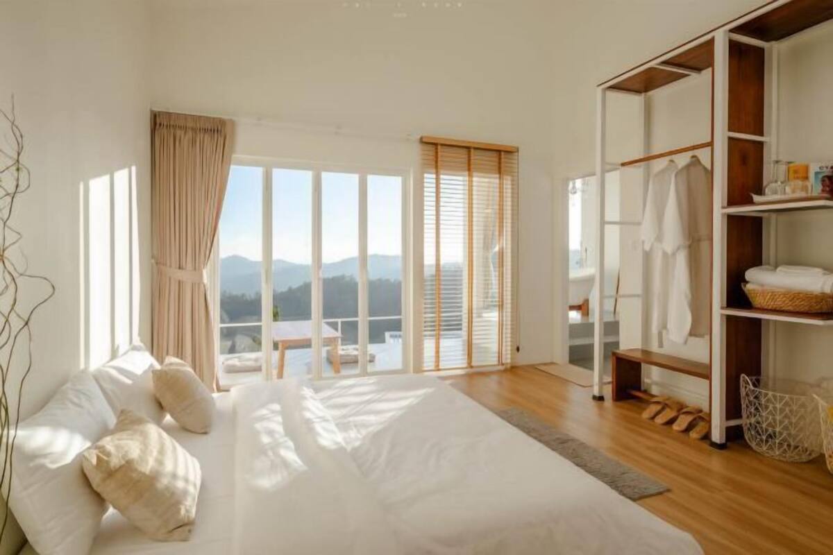 A bedroom with a large bed, a wardrobe, a window with a view, and a balcony.