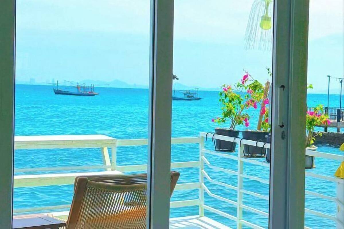 Un balcon avec vue sur la mer, une chaise et des plantes en pot.