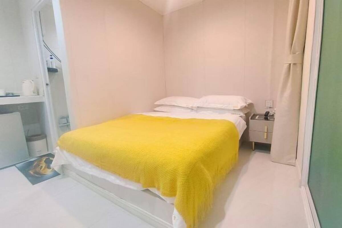 Une petite chambre à coucher, bien rangée, avec un lit, une table de chevet et une armoire.