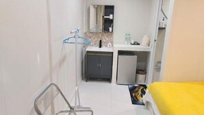 A narrow hotel room with a bed, a small kitchenette, a bathroom with a mirror, and a hallway leading to another room. - Rock Resort Koh Larn (Koh Larn)