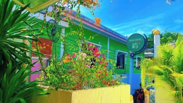 A colorful hotel exterior with a green and blue facade, a sign indicating 'Rock Hotel', and lush greenery around. - Rock Resort Koh Larn (Koh Larn)