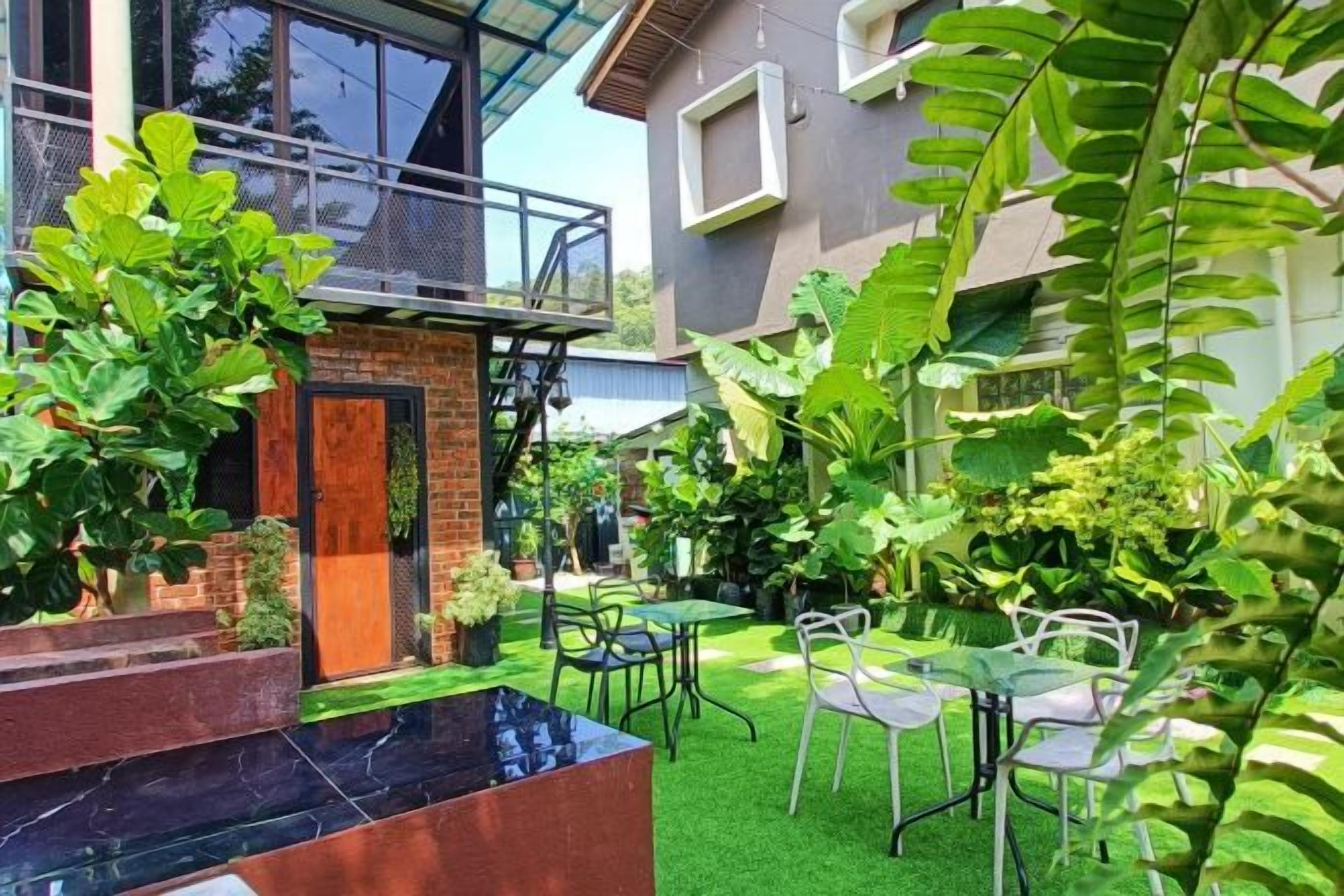 Una casa moderna con fachada de ladrillo, un balcón y un jardín cuidado con césped verde y diversas plantas.