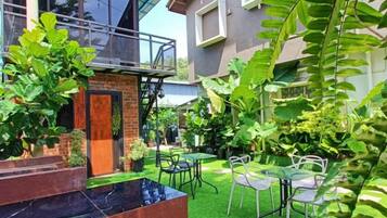 Una casa moderna con fachada de ladrillo, un balcón y un jardín cuidado con césped verde y diversas plantas.