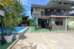 A hotel entrance with a reception desk, a pool area, and a covered outdoor seating area. - Tc Theme Park Guest House (Kuala Kuantan)