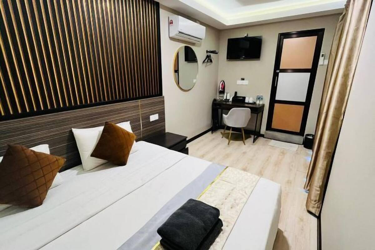Una habitación de hotel con cama, escritorio, silla, televisor y puerta.