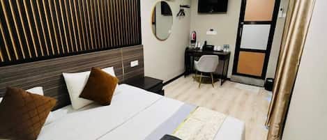 Una habitación de hotel con cama, escritorio, silla, televisor y puerta.