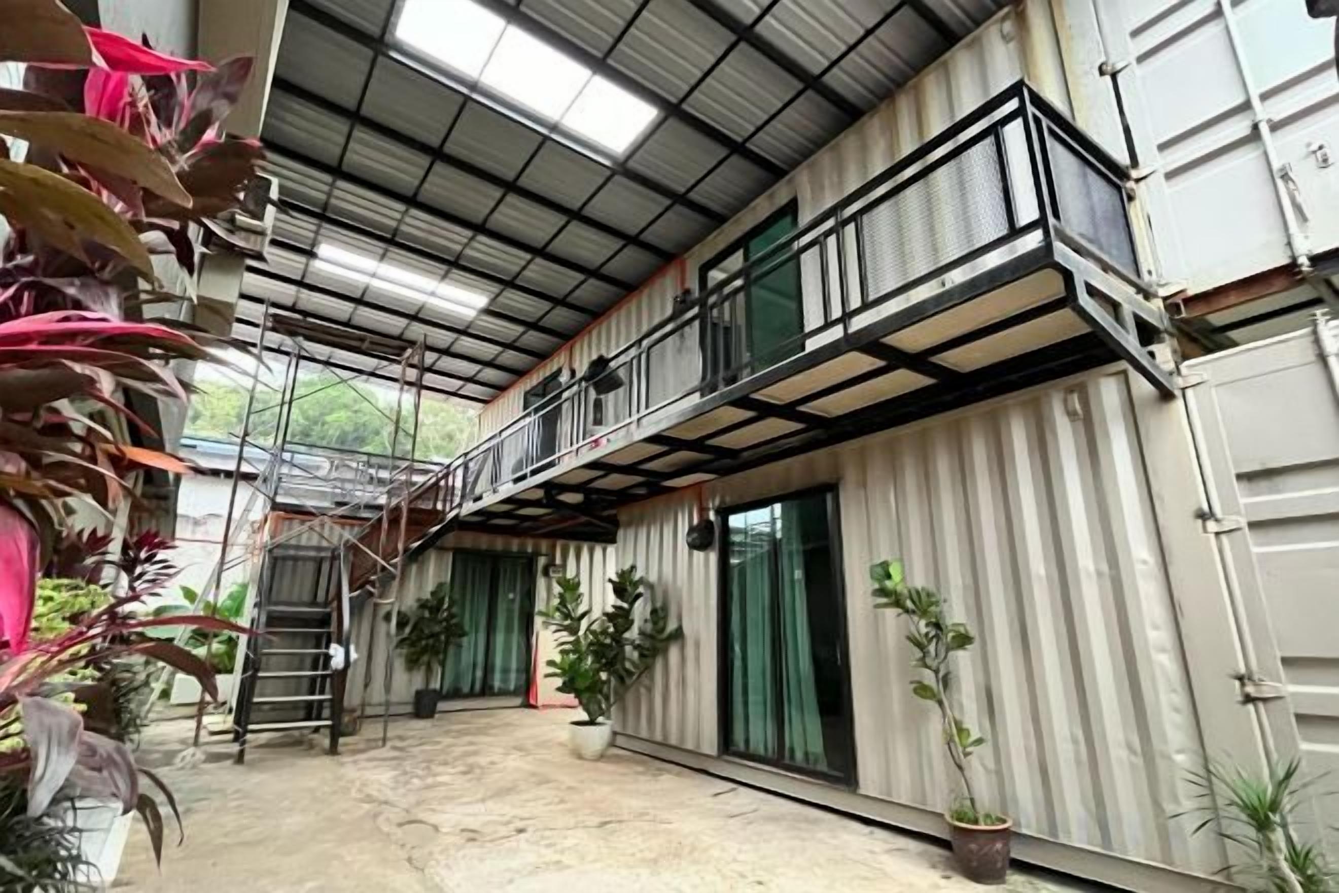 A multi-level building with a balcony, potted plants, and a ladder.