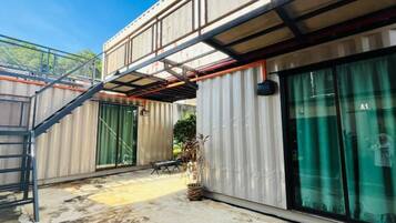 A modern building with a metal exterior, large sliding glass doors, and a staircase leading to an upper level.
