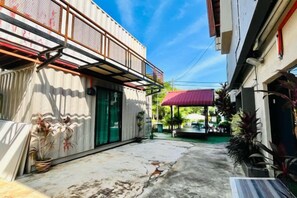 Une ruelle étroite, avec un immeuble sur la gauche et une zone abritée sur la droite.