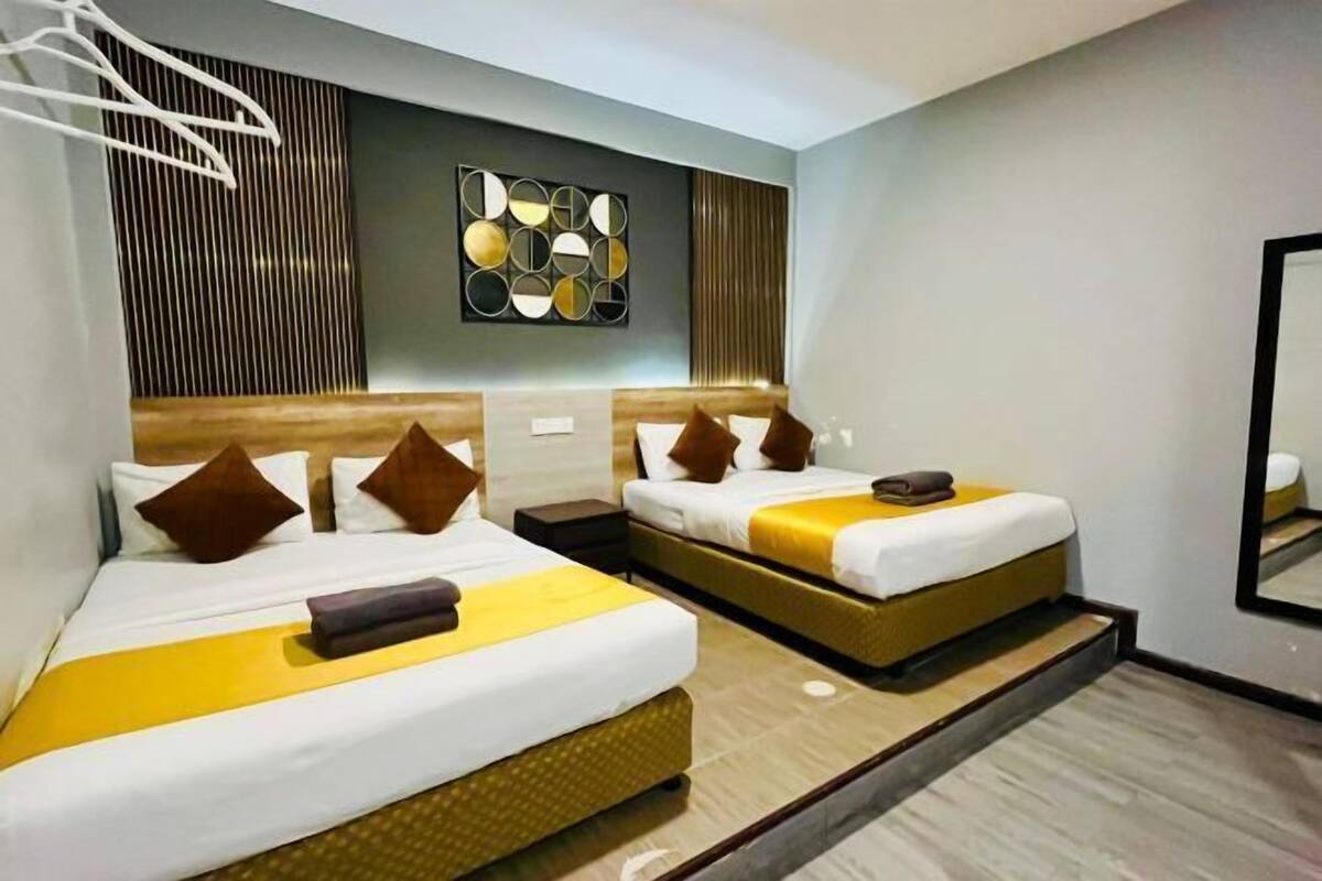 Habitación de hotel con dos camas, una obra de arte moderna en la pared y un espejo.