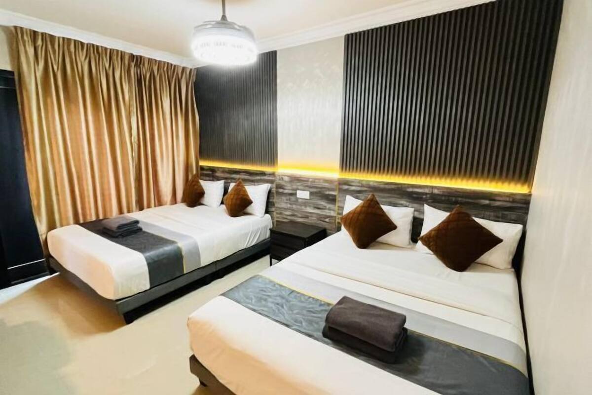 Habitación de hotel con dos camas, un ventanal grande con cortinas, una lámpara moderna y un diseño de pared texturizado.