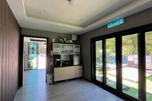 A modern kitchen with built-in appliances, a sliding glass door leading to a patio, and a sign indicating the name of the property. - Tc Theme Park Guest House (Kuala Kuantan)