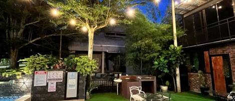 An outdoor patio area with a pool, seating, and a building in the background.