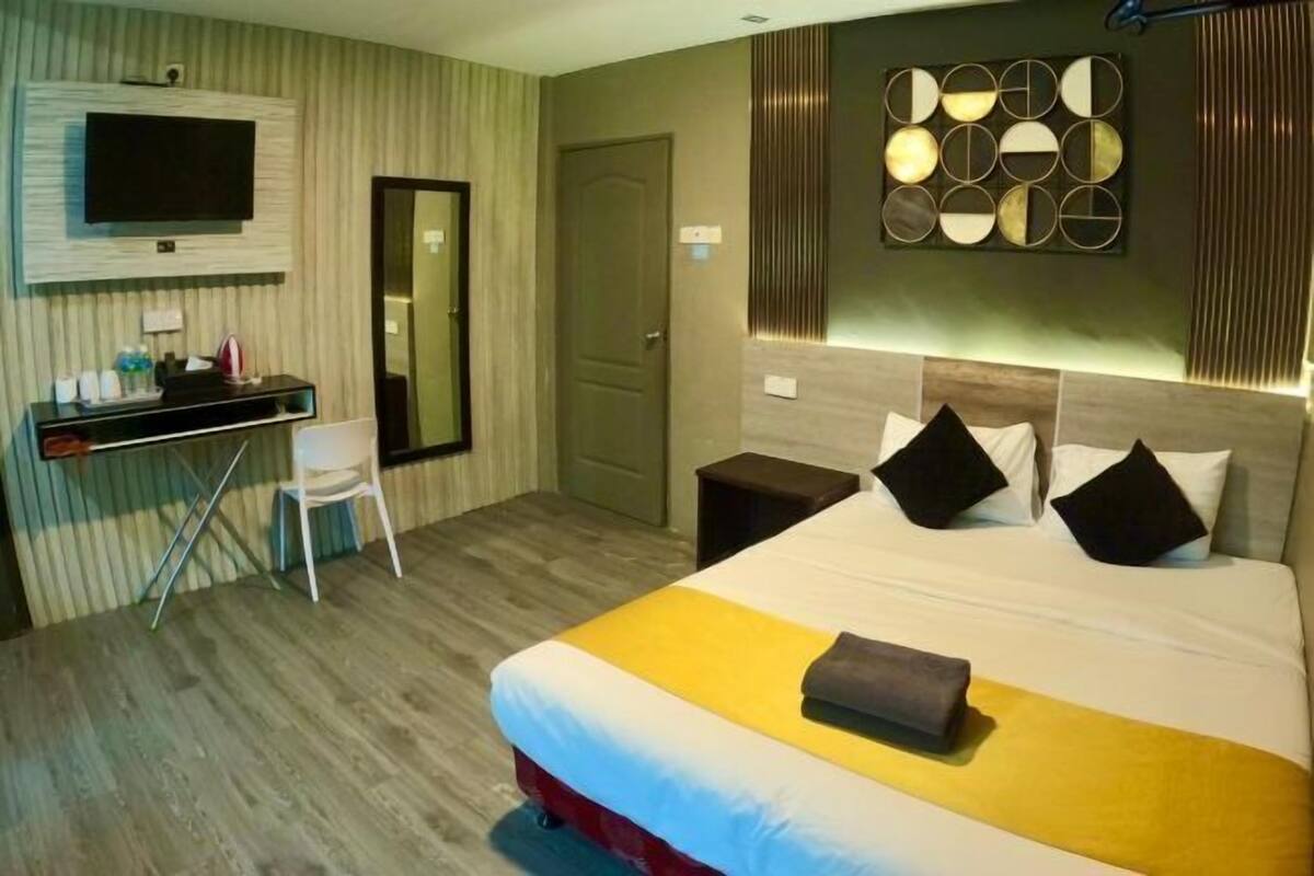 Una habitación de hotel con cama, escritorio, silla, televisión y un muro con espejos circulares.
