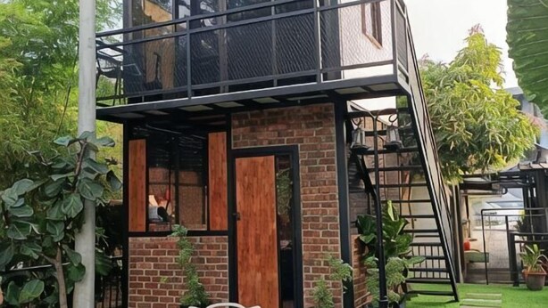 Ein modernes Haus mit Ziegelaußenwand, einer Holztür und einer Metalltreppe.