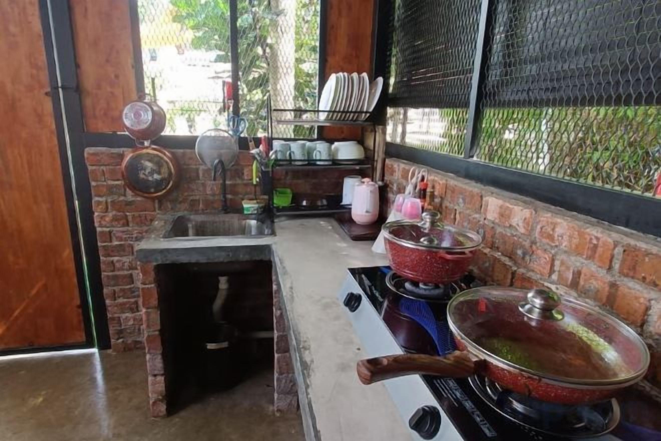 A kitchen with a brick wall, a gas stove, pots, and a sink.