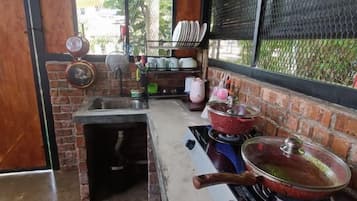 A kitchen with a brick wall, a gas stove, pots, and a sink.