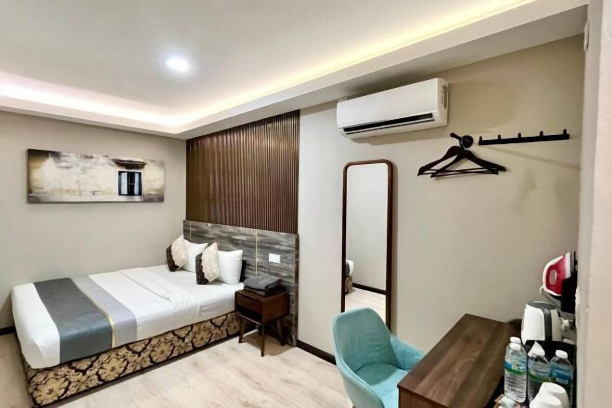Una habitación de hotel moderna con cama, mesita de noche, silla y escritorio con artículos de aseo.