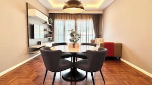Un espace repas moderne avec une table ronde, quatre chaises et un luminaire suspendu.