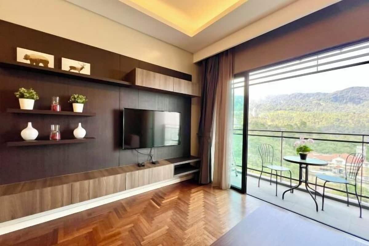 Una sala de estar moderna con una televisión de pantalla plana, suelo de madera y un balcón con sillas y una mesa.